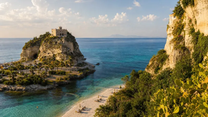 Spiaggia tranquilla sulla Costa degli Dei: la Calabria a settembre con mare calmo e luce dorata del tardo pomeriggio