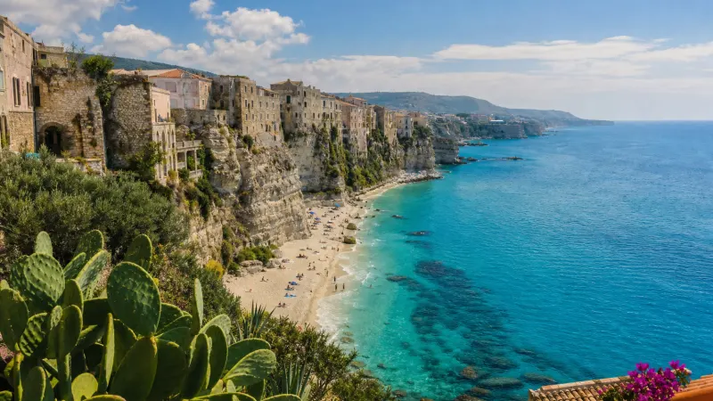 Castagne Calabria: caldarroste appena tolte dal fuoco in una padella forata, con ricci e foglie d'autunno e il mare sullo sfondo
