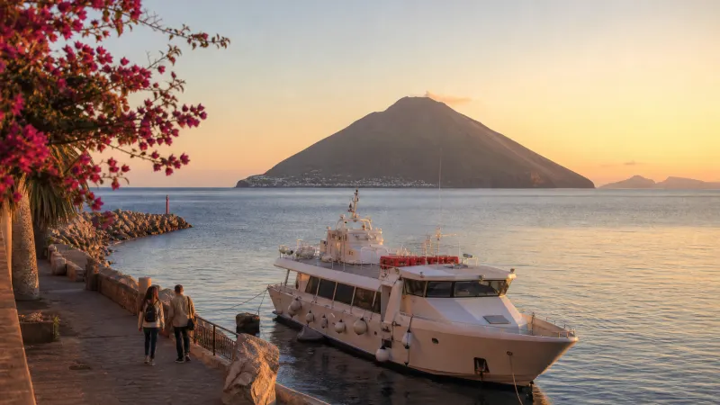 Escursione Eolie autunno: motonave ormeggiata nel porto di Tropea all'alba con la sagoma di Stromboli all'orizzonte